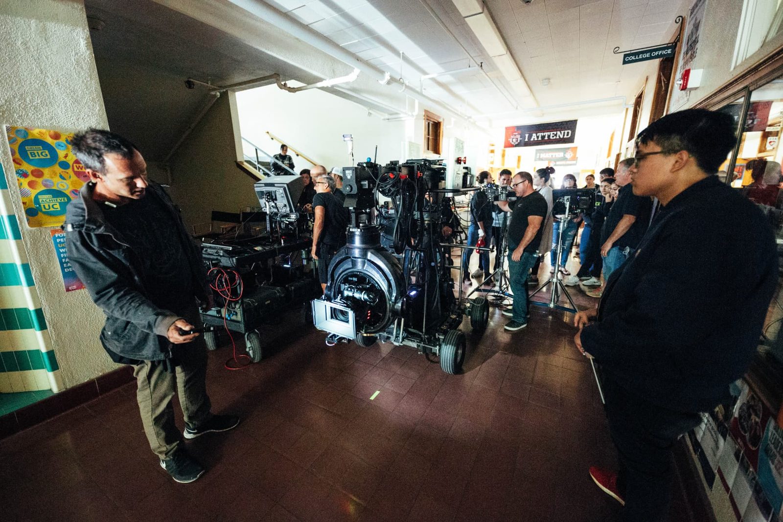 Crew and students gathered around a camera dolly in a school hallway