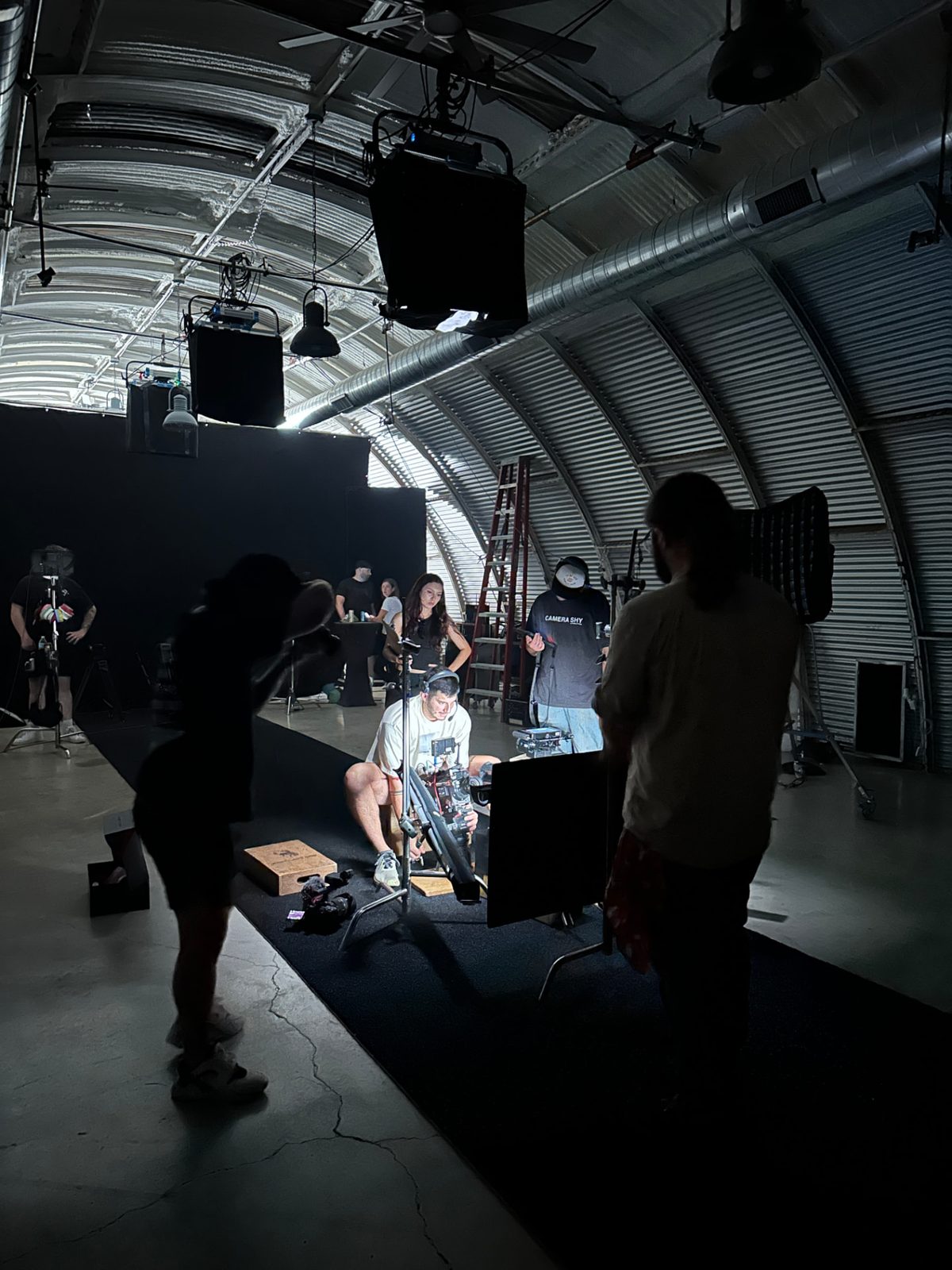 Crew working around a camera rig on a blacked-out studio stage