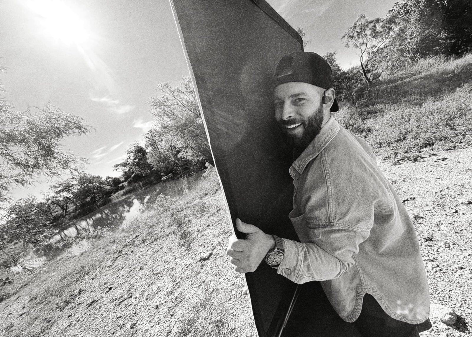 Crew member carrying a bounce along a ridge line, black and white
