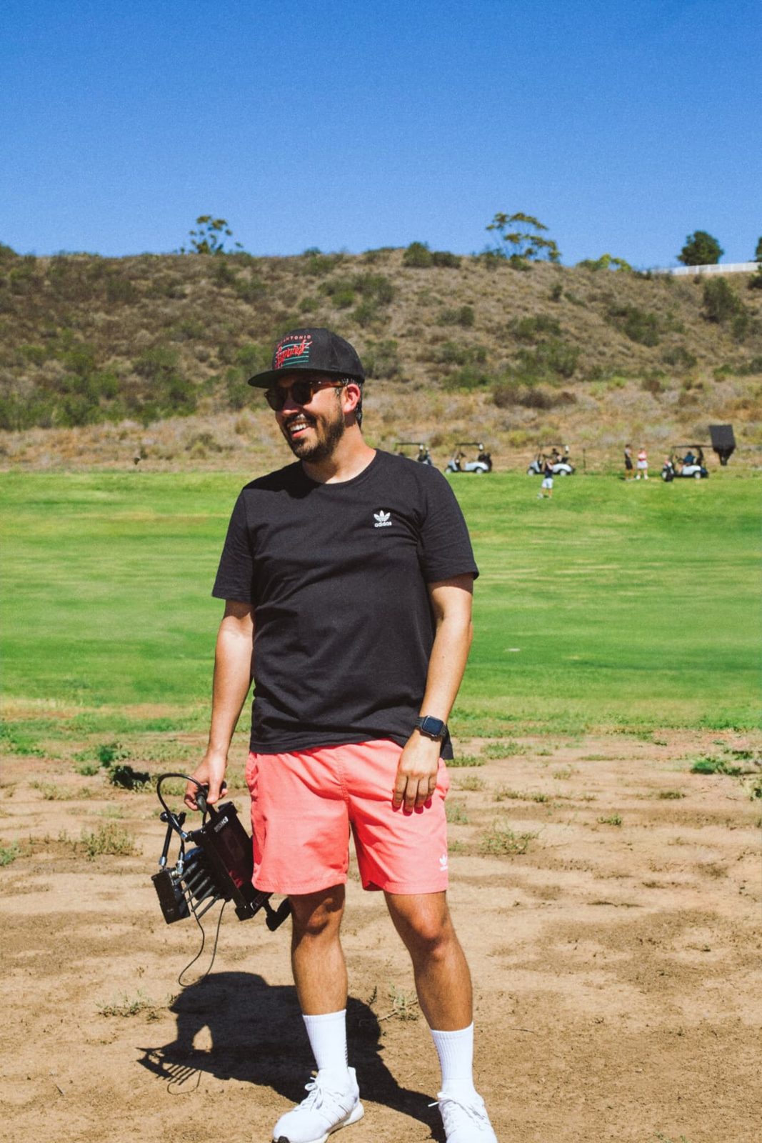 Crew member carrying a light kit across a golf course set