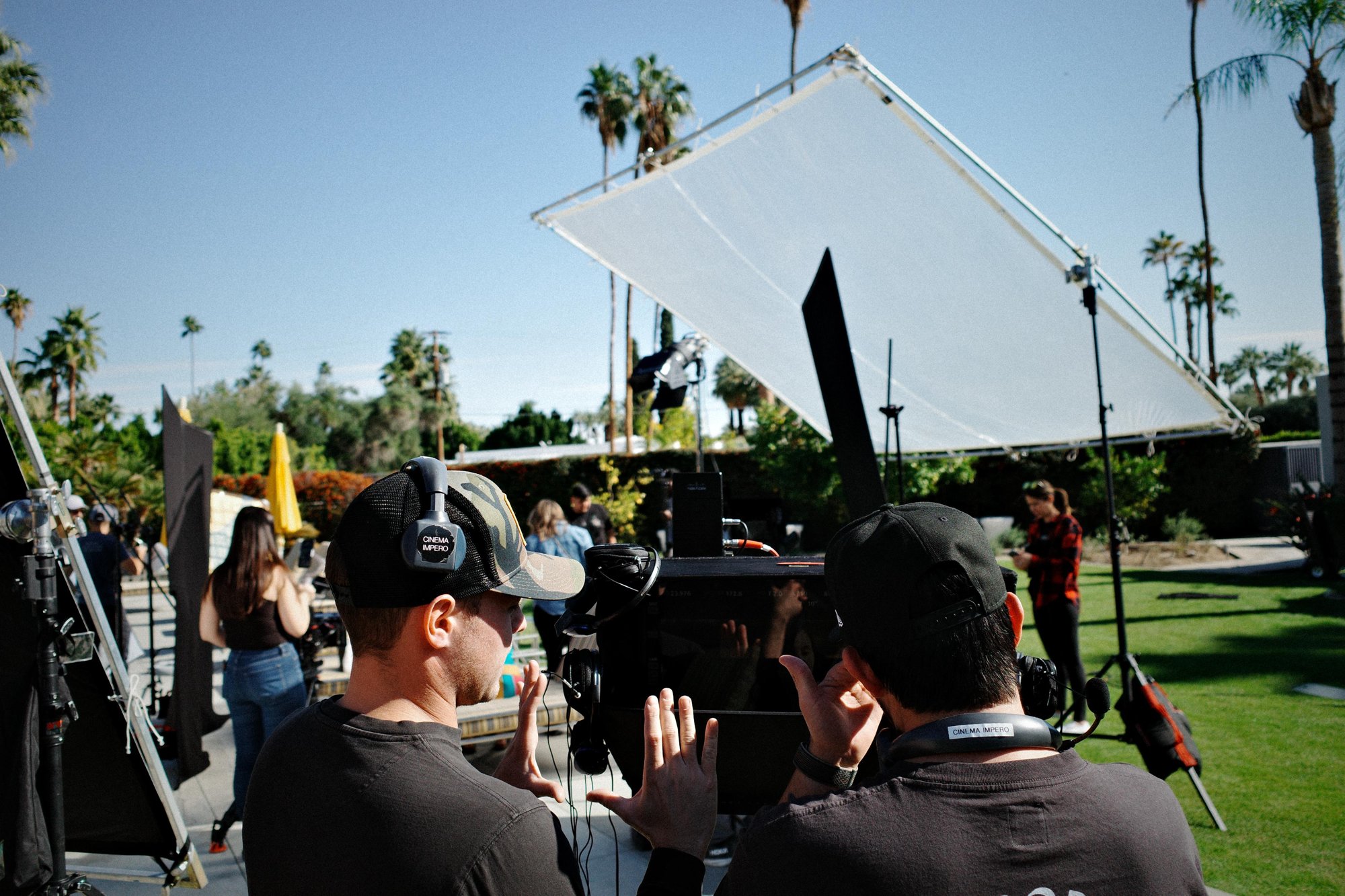 Directors reviewing the frame at an outdoor set among palm trees